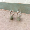 Silver earrings with green beads on a stone surface