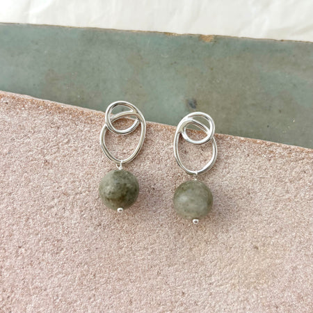 Silver earrings with green beads on a stone surface