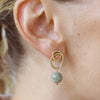 Close-up of an ear wearing a gold earring with a green bead.
