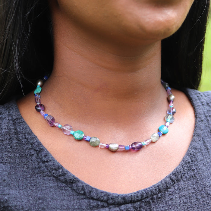 Necklace with multicolored beads worn by a person against a neutral background