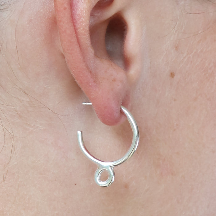 Silver hoop earring worn on a person's ear